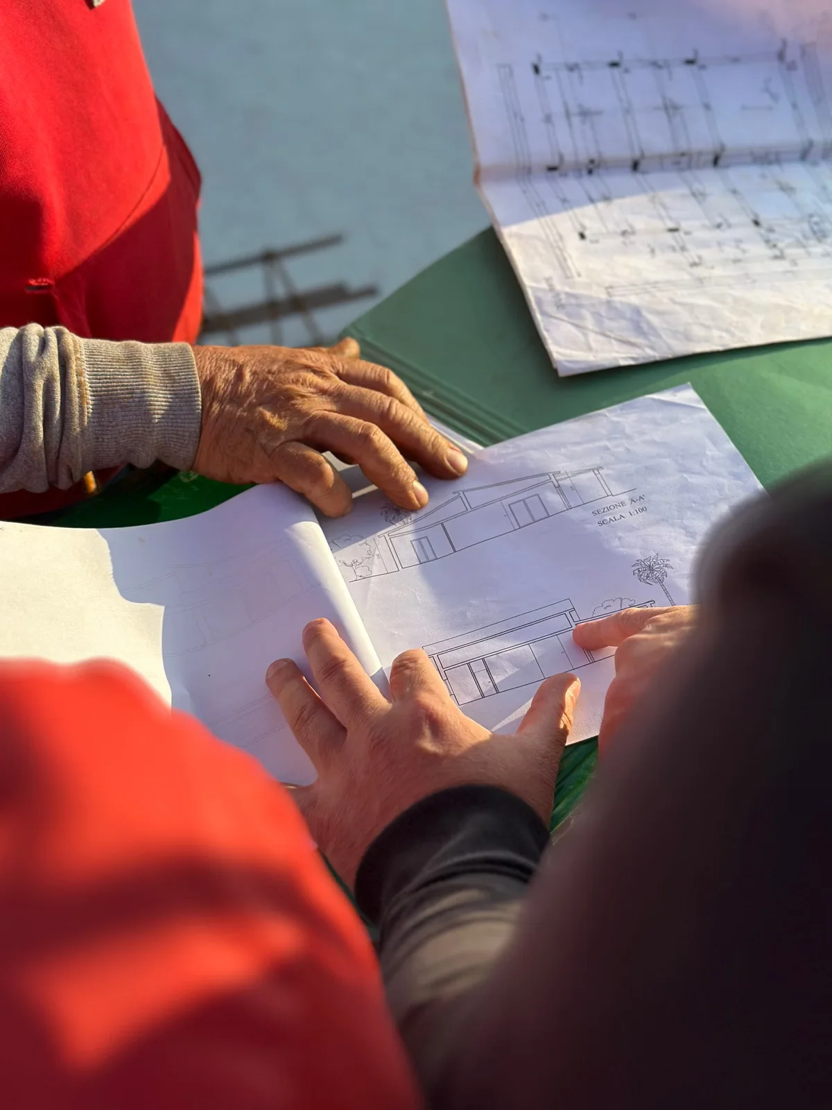 Professionnels examinant des plans sur chantier, illustrant la décomposition technique d'un budget de terrasse