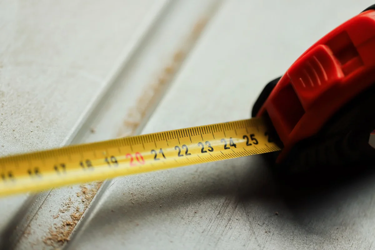 Mètre ruban sur une surface de chantier, illustrant la mesure de la réservation disponible sous un seuil