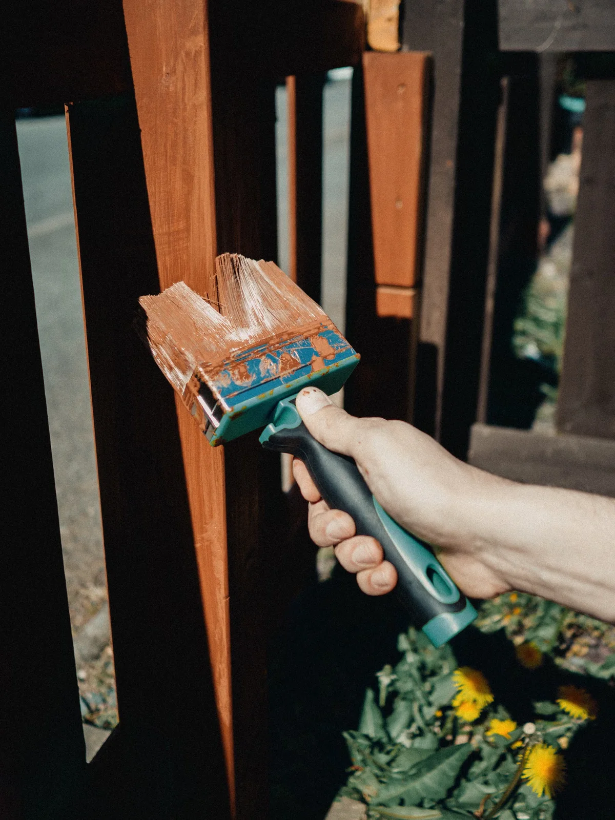 Application manuelle d'une protection sur du bois en extérieur, illustrant une finition sobre appliquée en couche maîtrisée