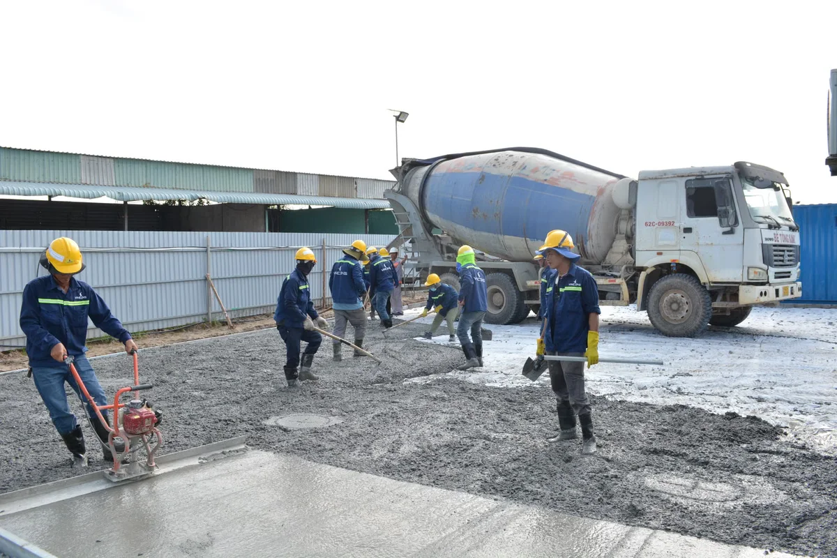 Équipe coulant du béton sur un chantier extérieur, illustration d'une dalle qui doit être conçue, nivelée et drainée avant de recevoir une terrasse