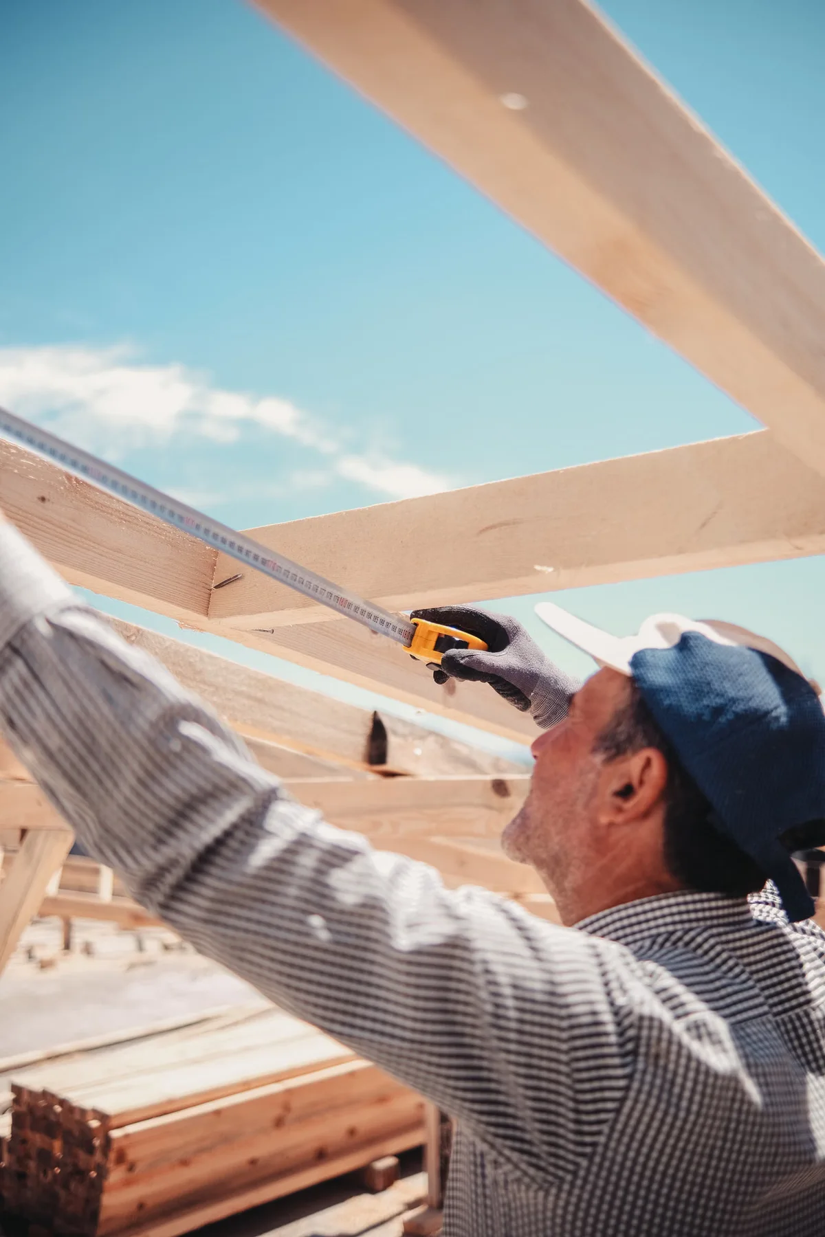Charpentier mesurant des éléments de structure en bois, rappel de la distinction entre platelage, lambourdes et éléments structurels