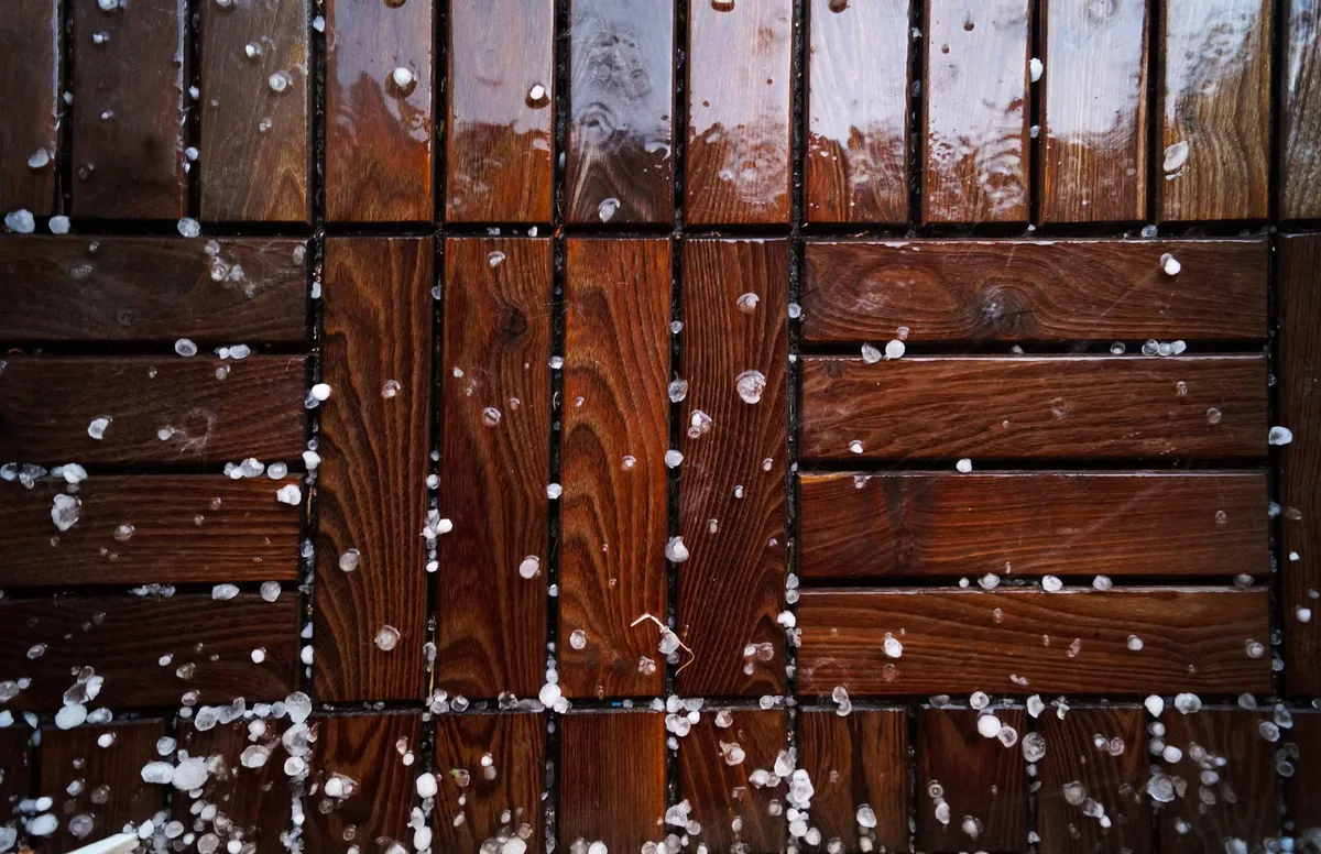 Lames de bois mouillées avec neige fondante, illustration des contraintes de froid, d'humidité et de gel à vérifier avant une pose hivernale