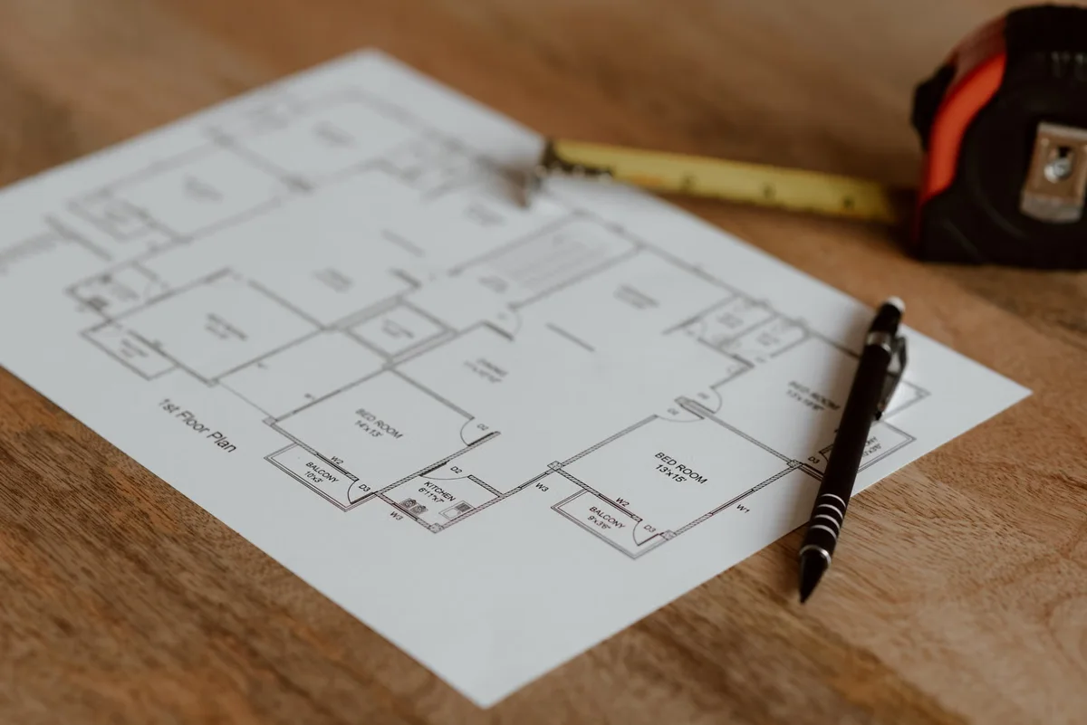 Plan de construction, mètre et stylo sur une surface en bois pour illustrer la lecture détaillée d'un devis