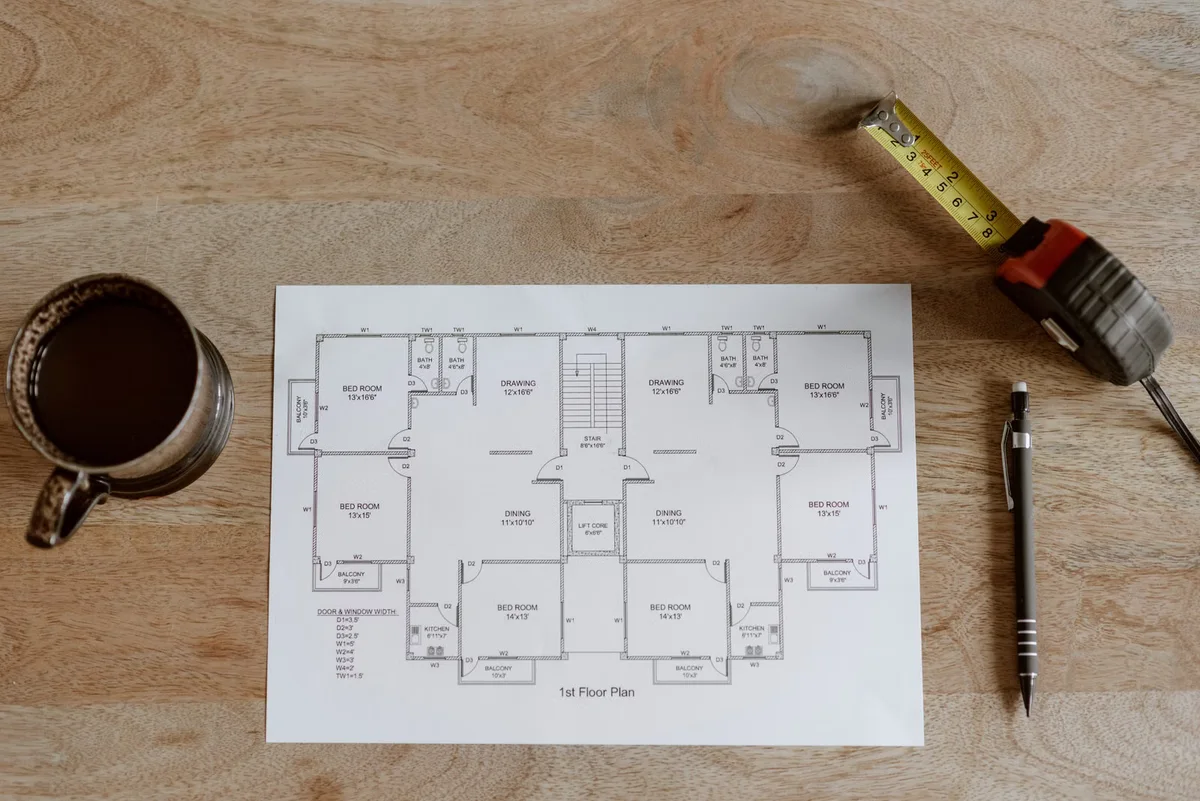 Plan, mètre et outils de préparation illustrant les postes à chiffrer séparément dans un projet de terrasse