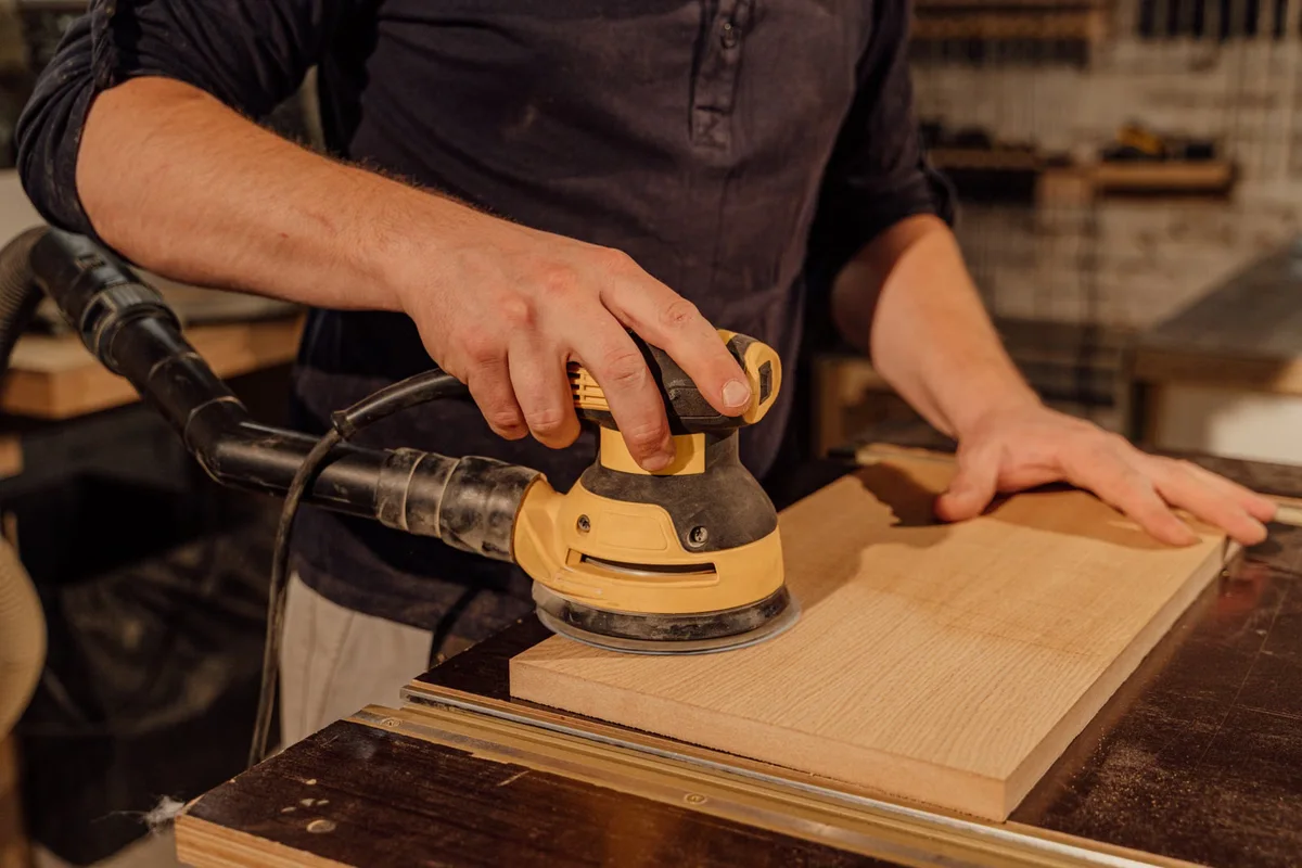 Ponçage d'une planche en bois avant finition, exemple de préparation de surface lorsque l'état du bois l'exige