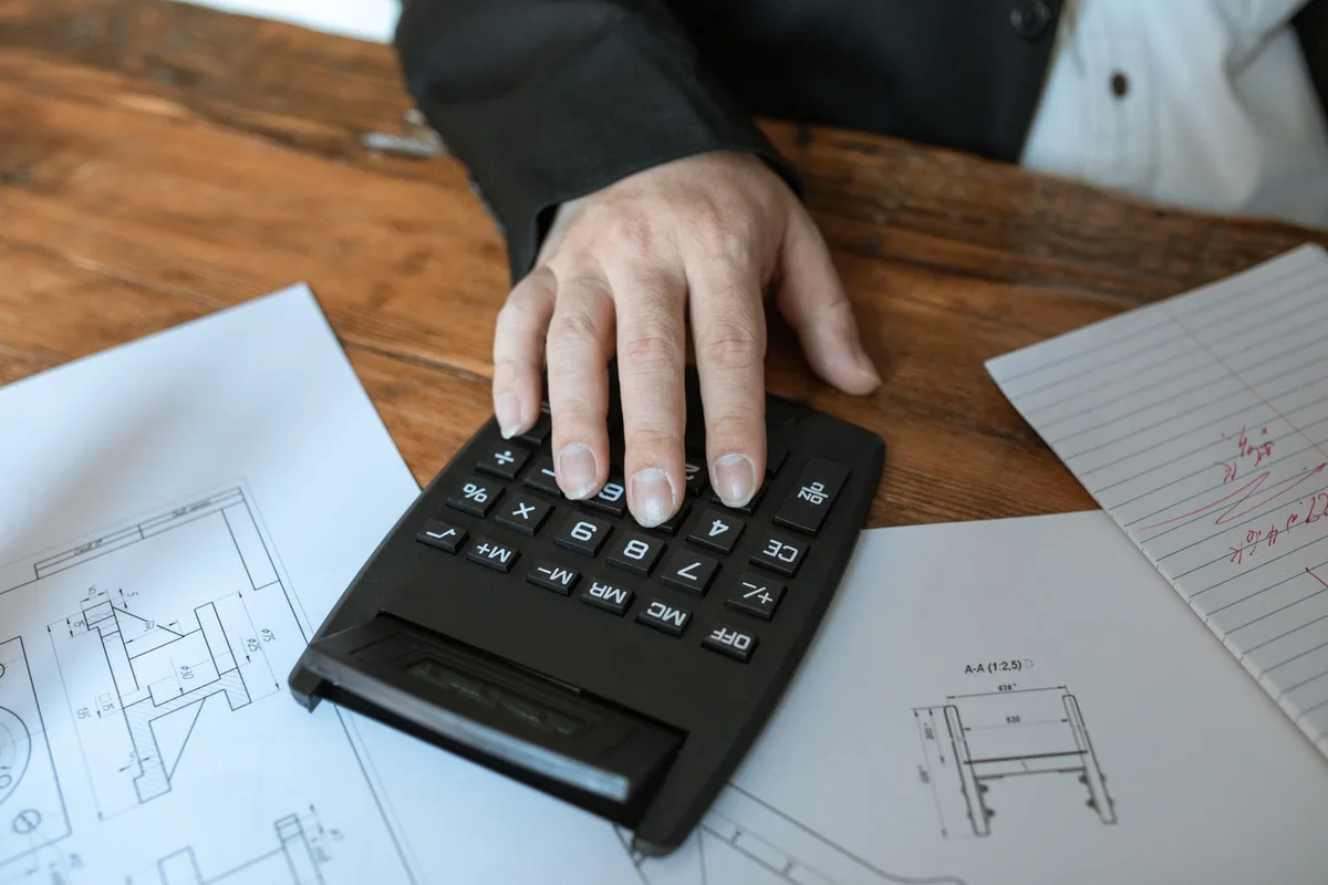 Calculatrice utilisée à côté de documents de travail, illustration de l'écart de montant TTC produit par un taux de TVA différent