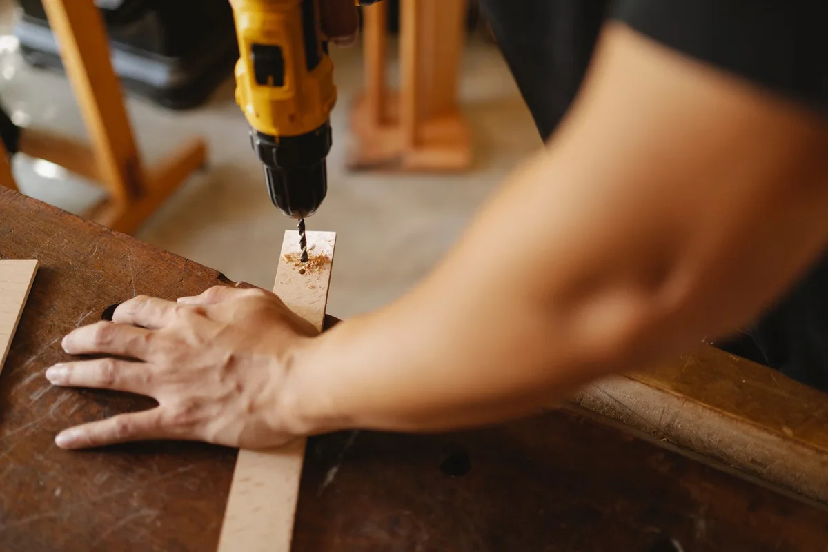 Préperçage d'une pièce de bois avec une perceuse avant la mise en place d'une fixation