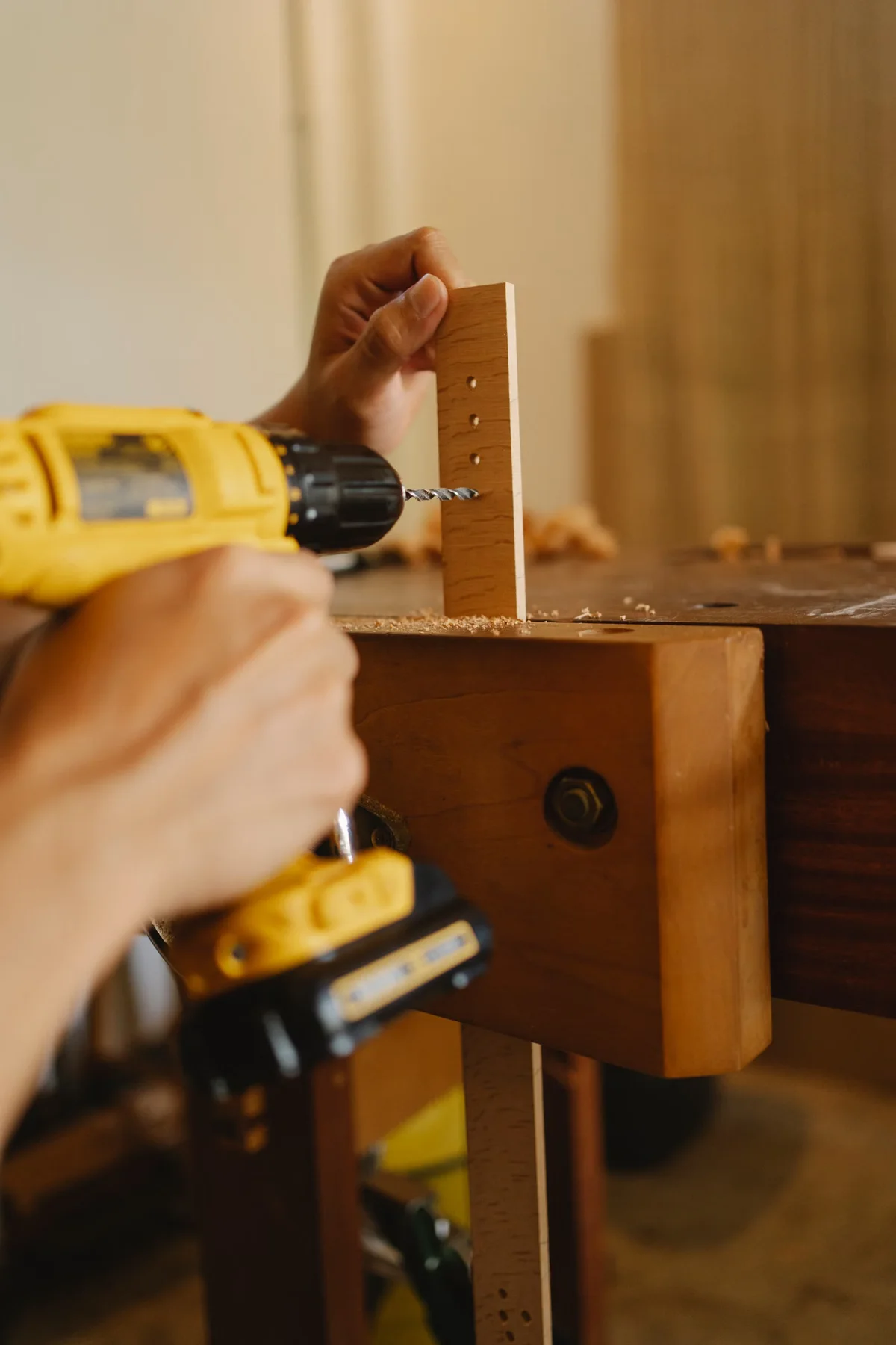 Artisan perçant précisément une pièce de bois, illustration du choix et de la mise en œuvre des fixations selon le système de terrasse