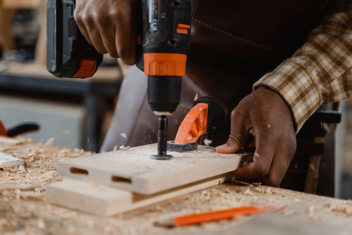 Menuisier perçant une pièce de bois avec précision, illustration du temps de préparation et de pose associé aux systèmes de fixation