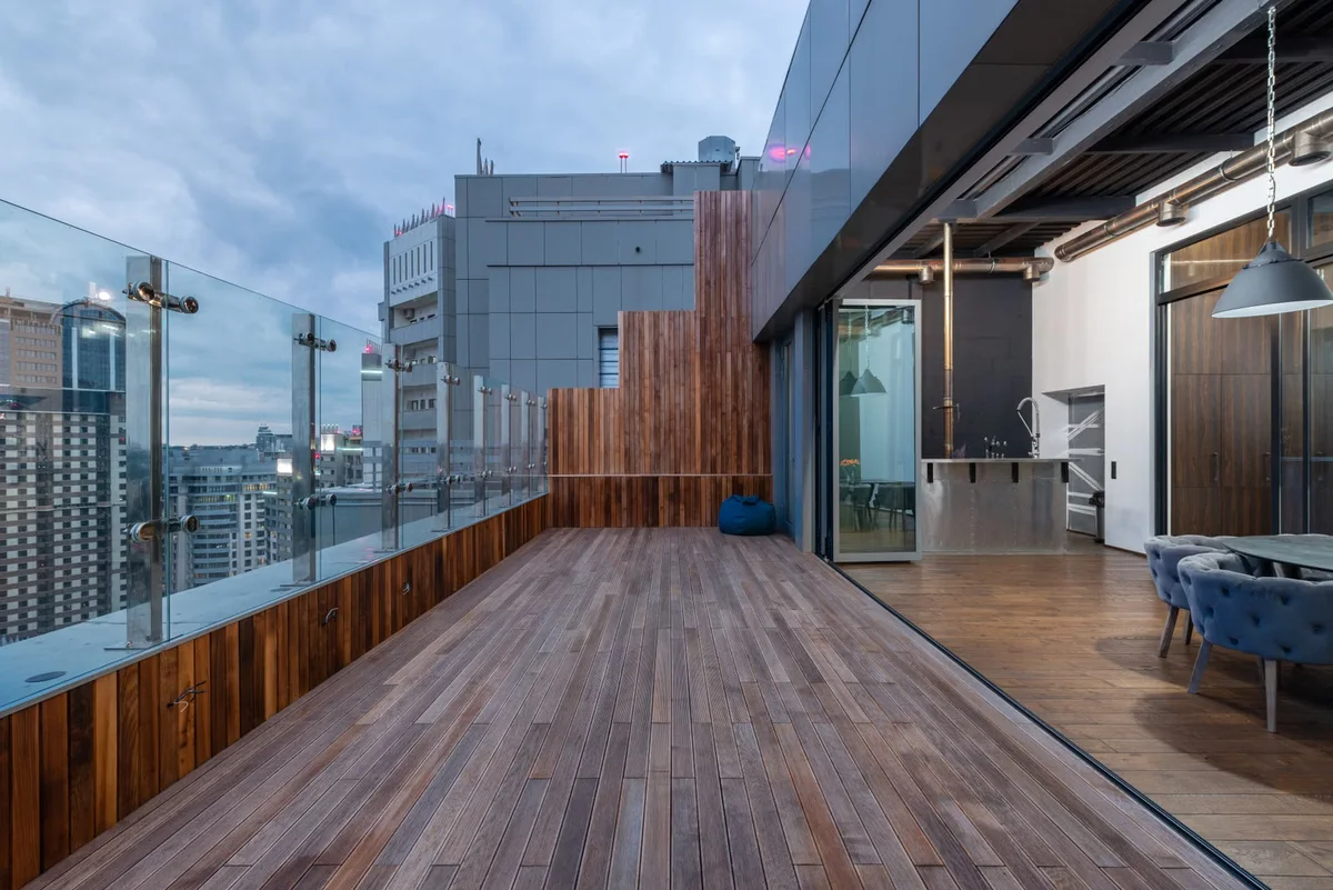 Grande terrasse en hauteur avec plancher bois et garde-corps, illustration des contraintes particulières de charge, d'étanchéité et d'évacuation sur balcon ou toiture-terrasse