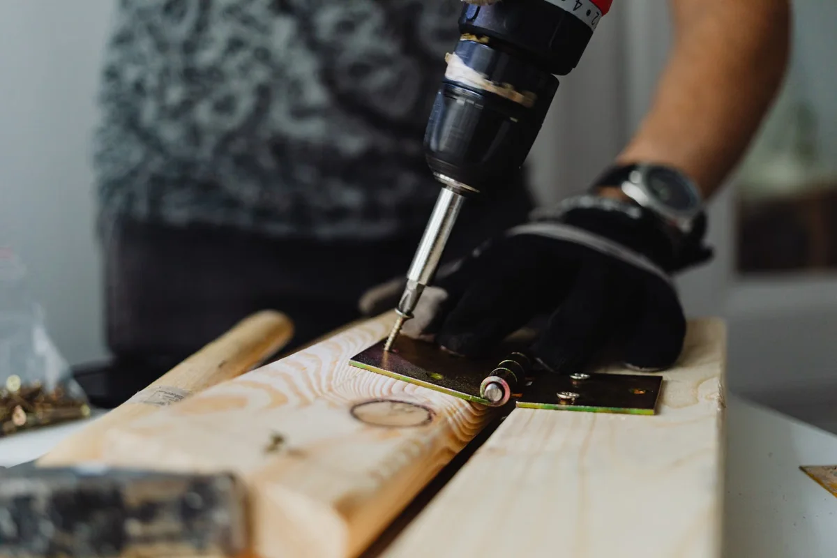 Vissage précis dans une planche de bois, étape caractéristique du remplacement d'une lame fixée mécaniquement