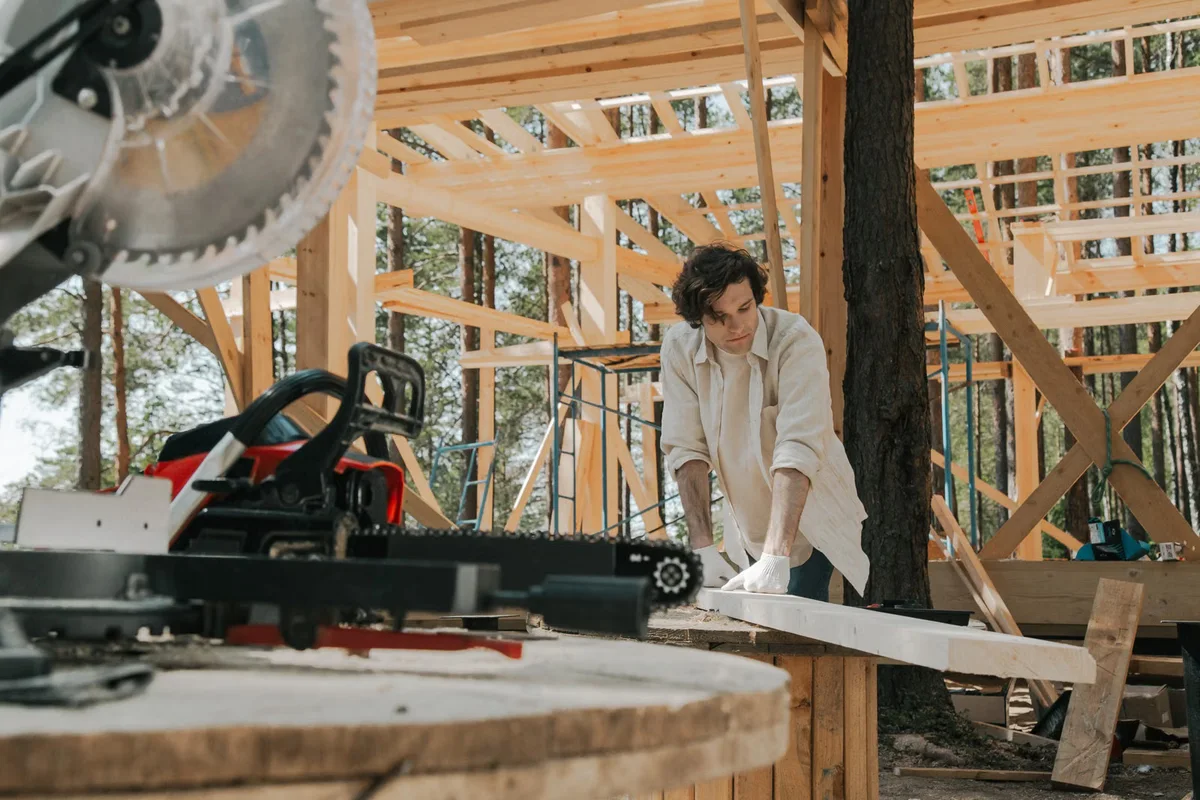 Charpentier travaillant sur une structure en bois, illustration de la partie porteuse invisible qui conditionne rigidité et durabilité