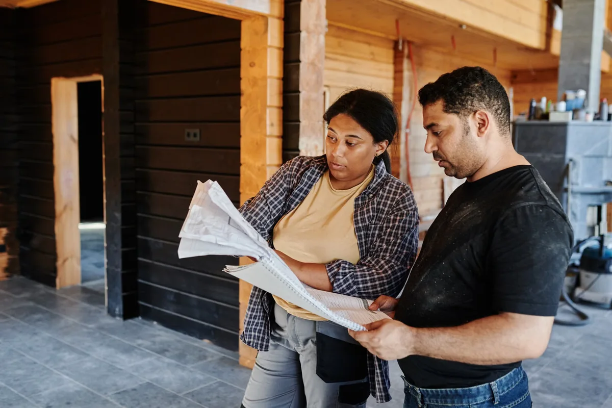 Professionnels consultant un plan de construction, illustration des étapes à coordonner avant de fixer un délai réaliste de chantier