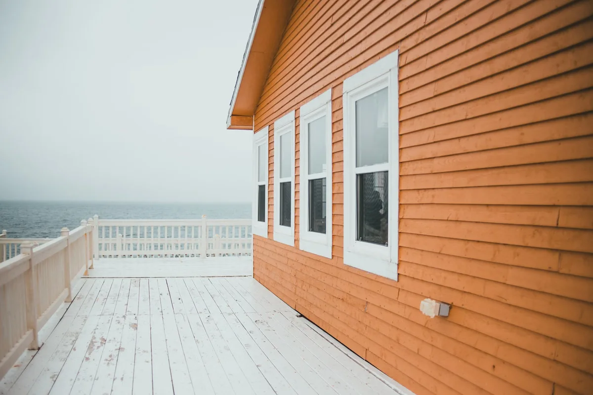 Maison en bois et terrasse en environnement marin, illustration d'un contexte où teintes, matériaux et fixations doivent être adaptés et clairement décrits