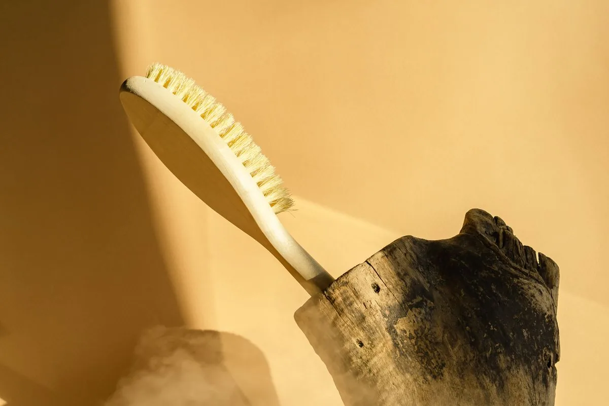 Brosse à fibres naturelles sur fond bois, rappelant le geste simple dont le temps augmente avec la surface à entretenir