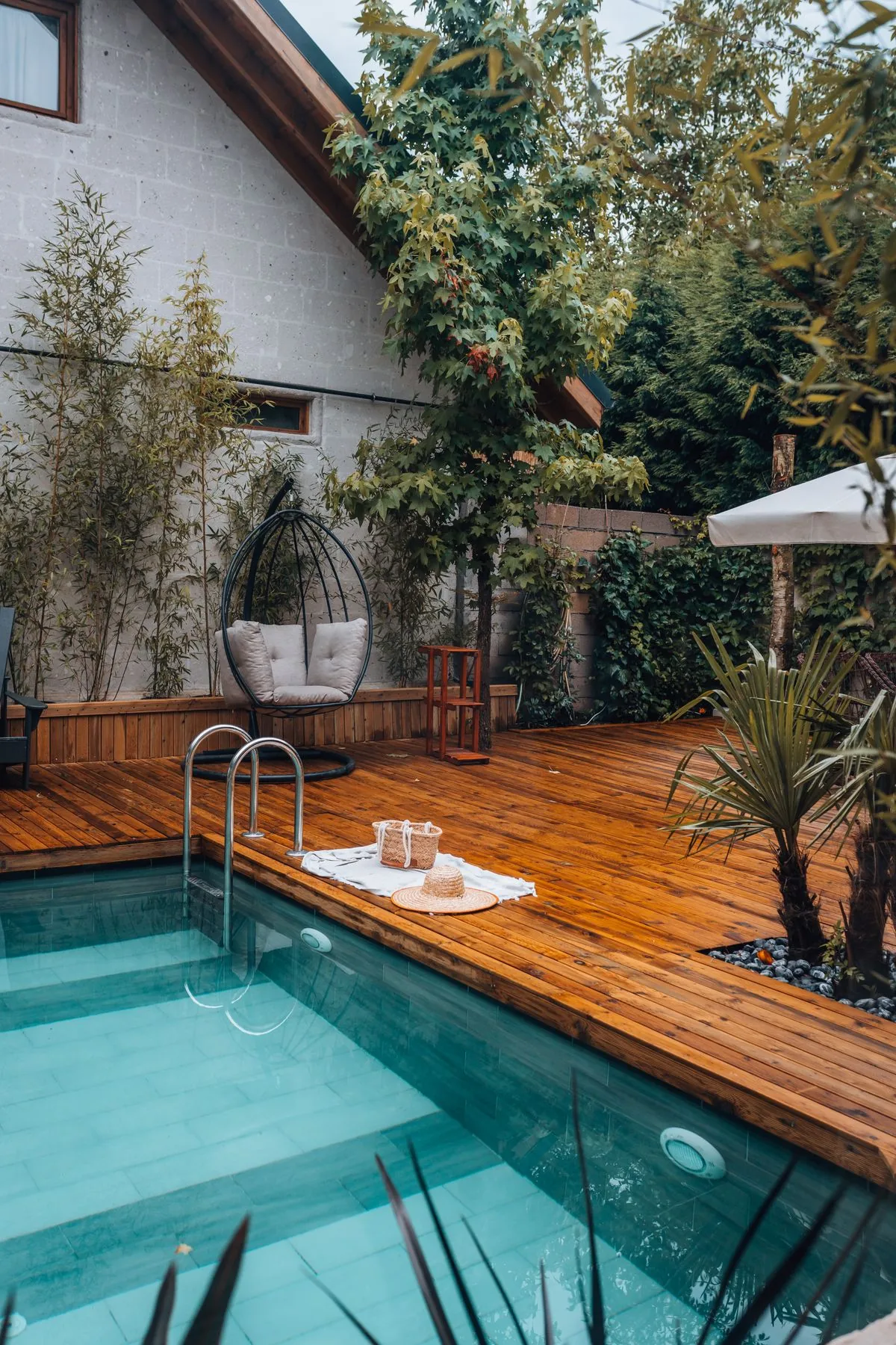 Piscine de jardin bordée d'un platelage en bois, illustration des contraintes d'humidité à prendre en compte avec des bois plus économiques