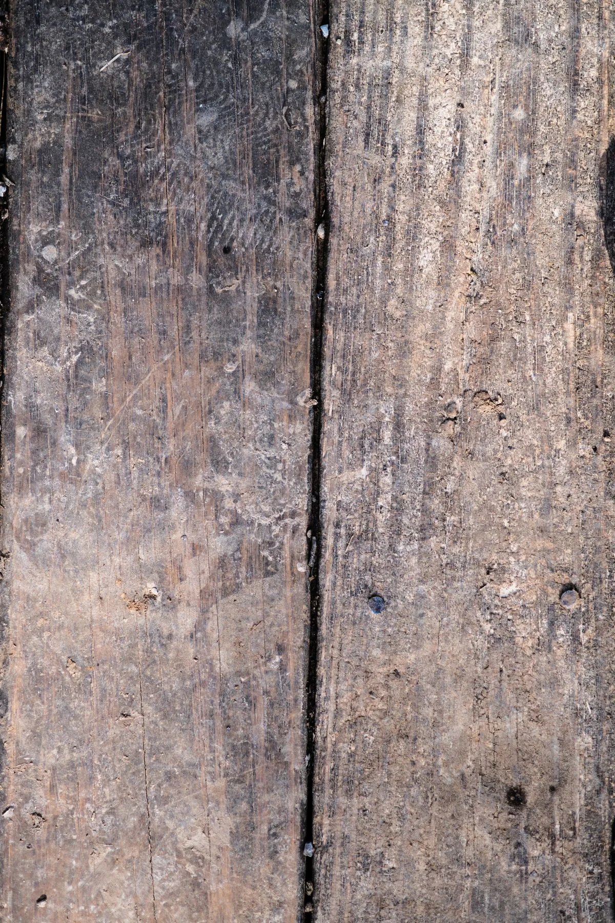 Surface de planches en bois patinées illustrant les marques, l'usure et les besoins de remise en état au fil du temps