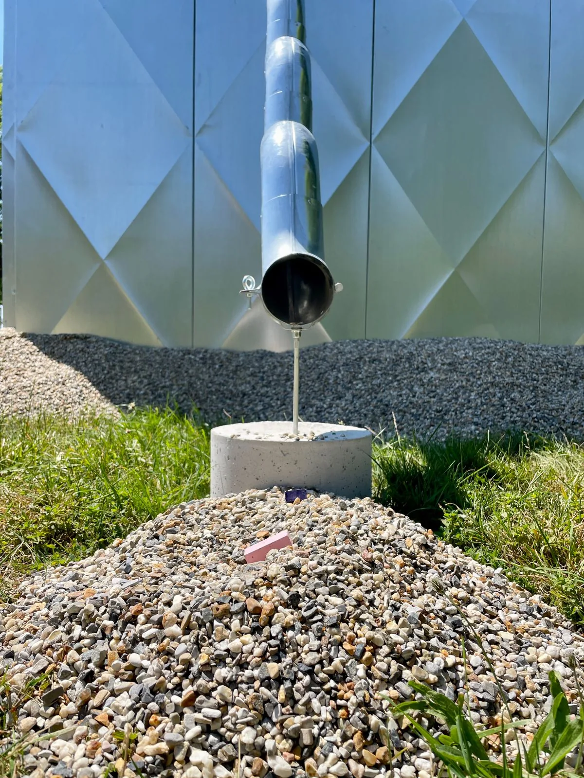 Évacuation d'eau par un conduit vers une zone minérale, illustrant la nécessité de prévoir un exutoire pour l'eau récupérée