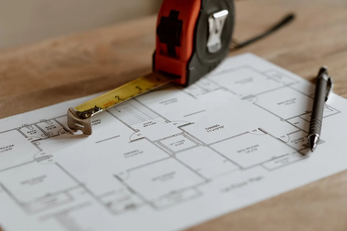 Plan de construction, mètre ruban et crayon préparés pour un chiffrage, illustration des facteurs qui font varier le prix posé d'une terrasse