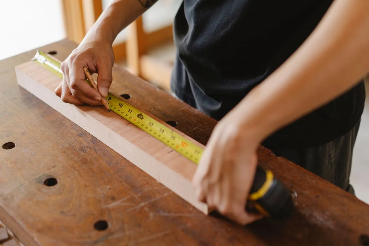 Mesure précise d'une pièce de bois au mètre ruban avant le calepinage d'une structure
