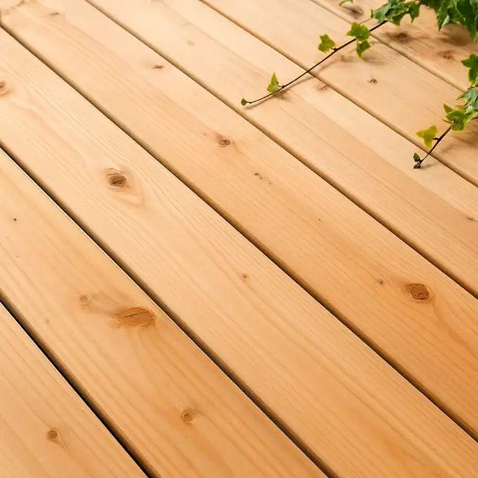 Lames de terrasse en bois Douglas rosé, avec veinage naturel et nœuds visibles, posées en extérieur sous une lumière naturelle.